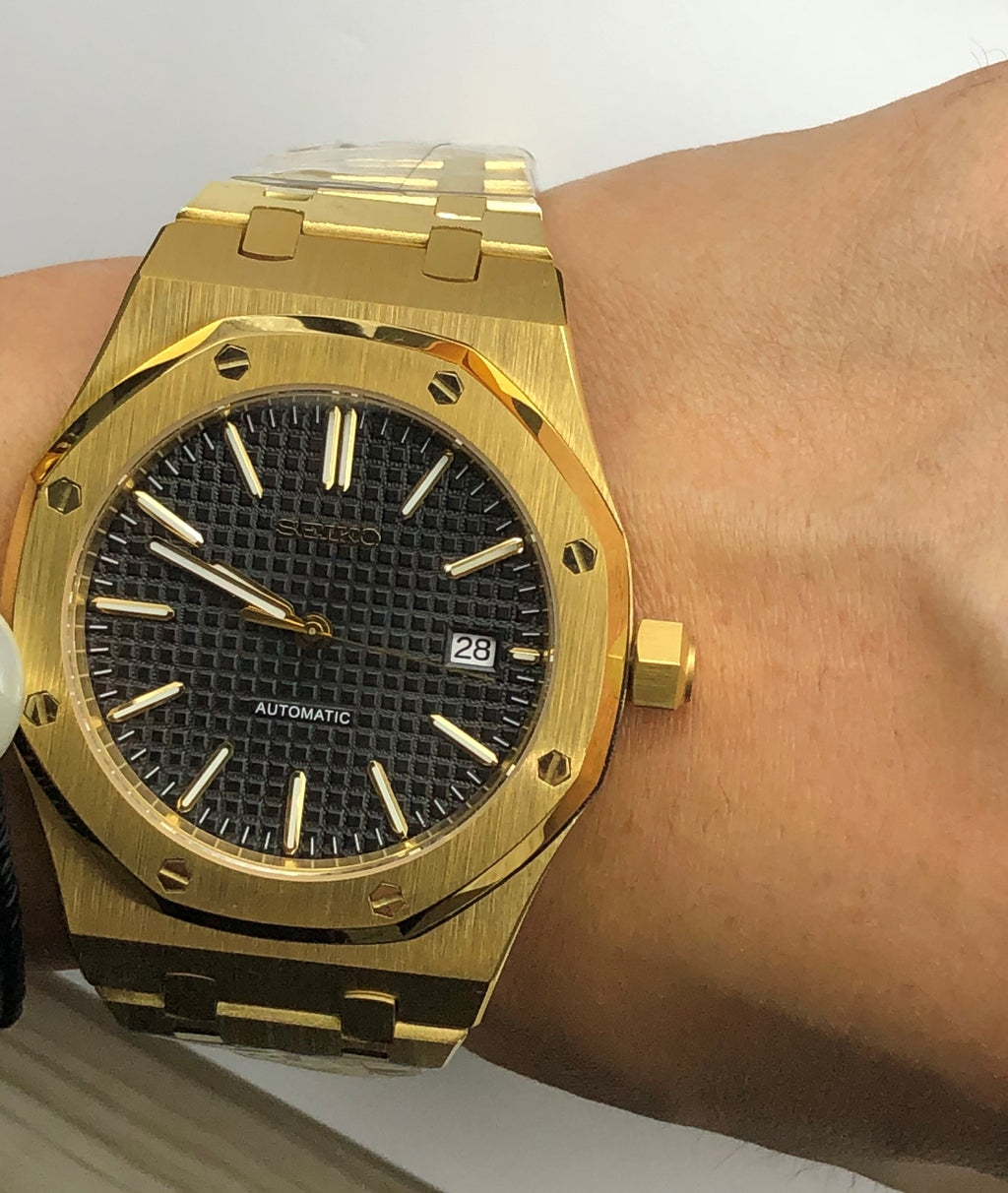 Seiko Mod dorée à cadran noir portée au poignet